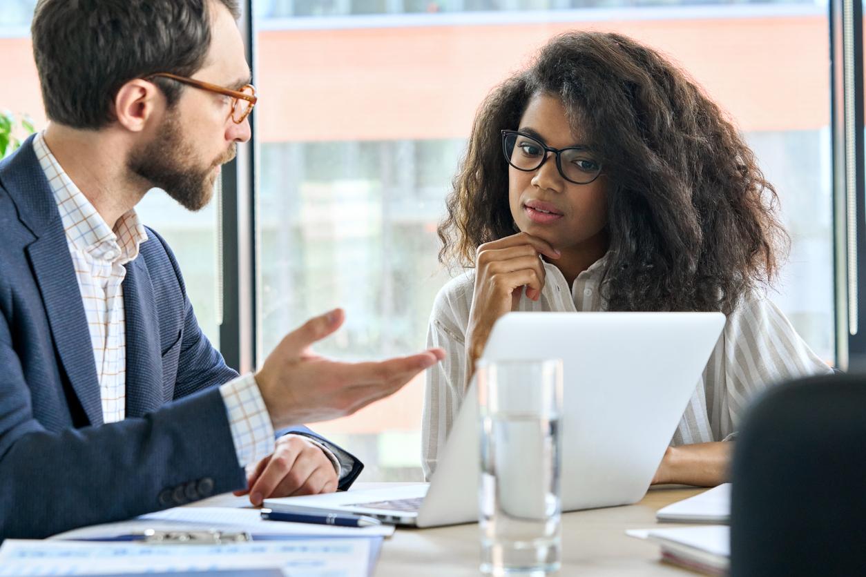 A white male academic talking to a young Black female student